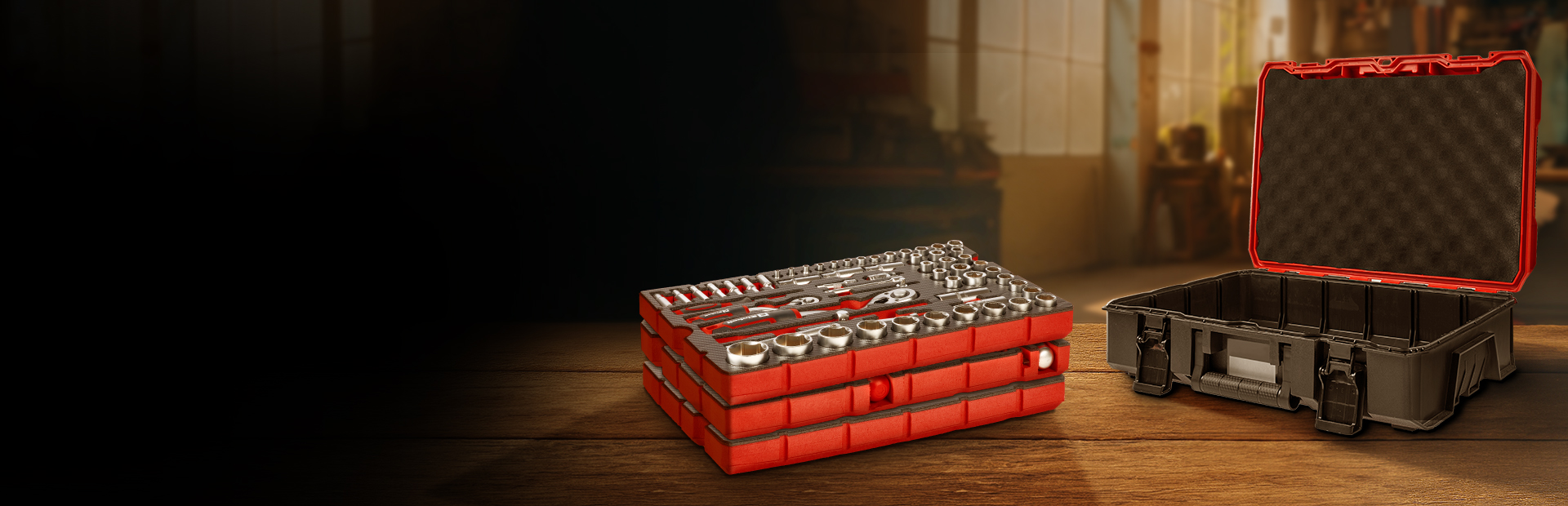 Stacked red tool trays with sockets and wrenches next to an open empty black tool case on a wooden surface.